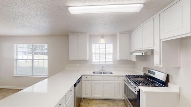 kitchen featuring appliances with stainless steel finishes, a sink, under cabinet range hood, a textured ceiling, and white cabinets