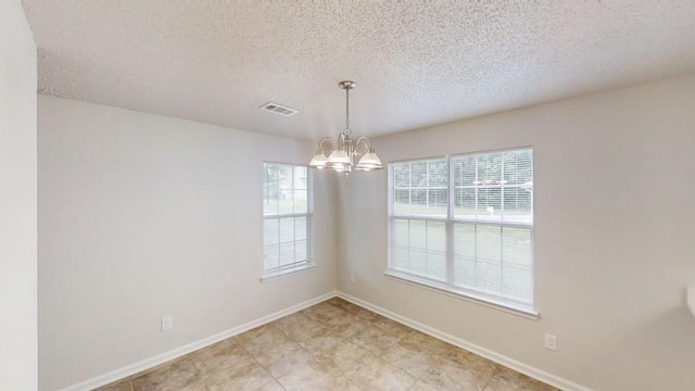 unfurnished dining area with a textured ceiling, plenty of natural light, a chandelier, and baseboards