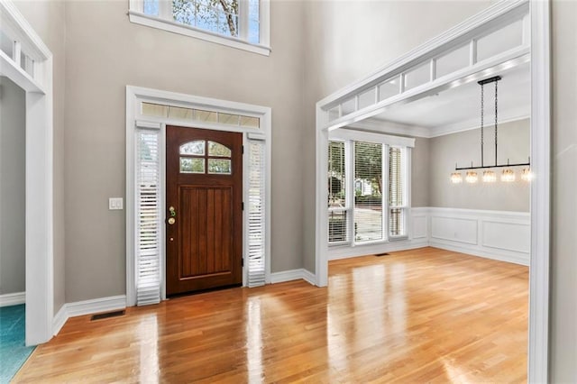 entrance foyer featuring ornamental molding, wood-type flooring, and a towering ceiling