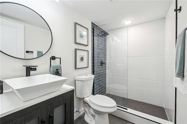 bathroom with vanity, a tile shower, and toilet