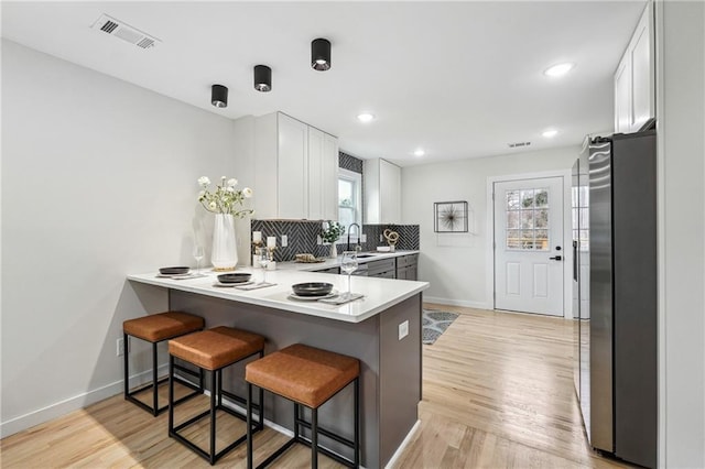 kitchen with white cabinets, sink, stainless steel fridge, and a kitchen bar