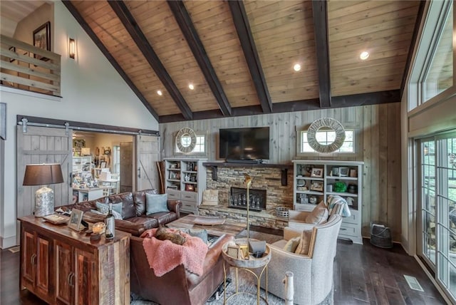 living room with dark wood-type flooring, a barn door, wooden walls, a fireplace, and beam ceiling