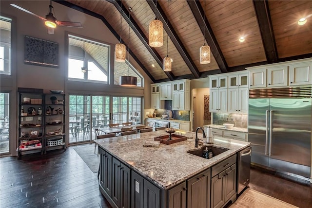 kitchen featuring high vaulted ceiling, tasteful backsplash, appliances with stainless steel finishes, white cabinetry, and a kitchen island with sink