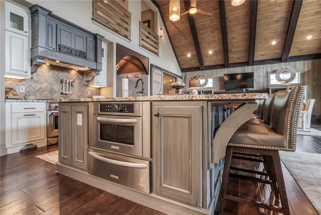 kitchen with ceiling fan, appliances with stainless steel finishes, wood ceiling, and light stone countertops