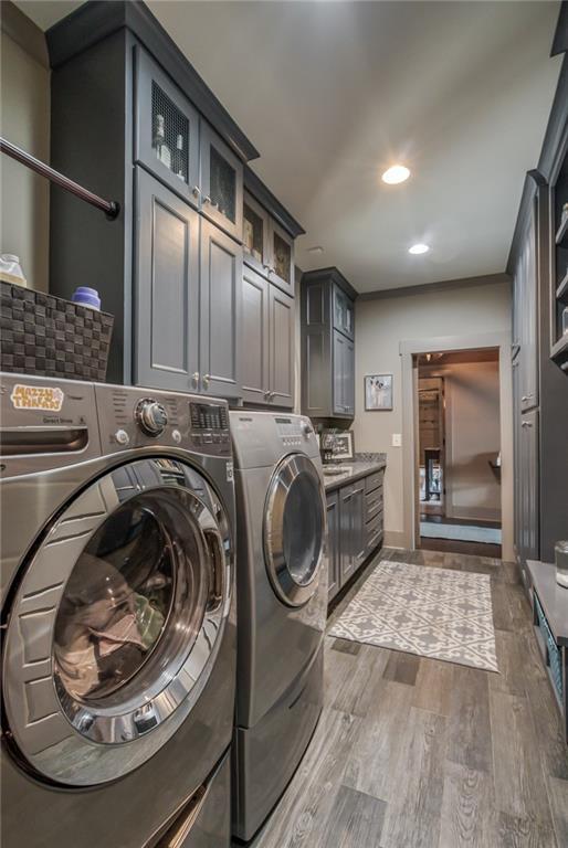 washroom featuring cabinets, washer and clothes dryer, and hardwood / wood-style flooring