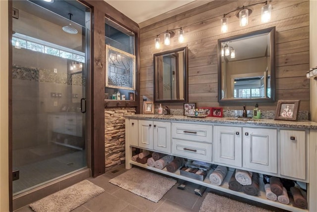 bathroom featuring wooden walls, tile floors, a shower with shower door, and double vanity