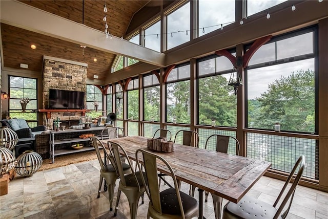 sunroom featuring wood ceiling, a fireplace, vaulted ceiling, and a wealth of natural light