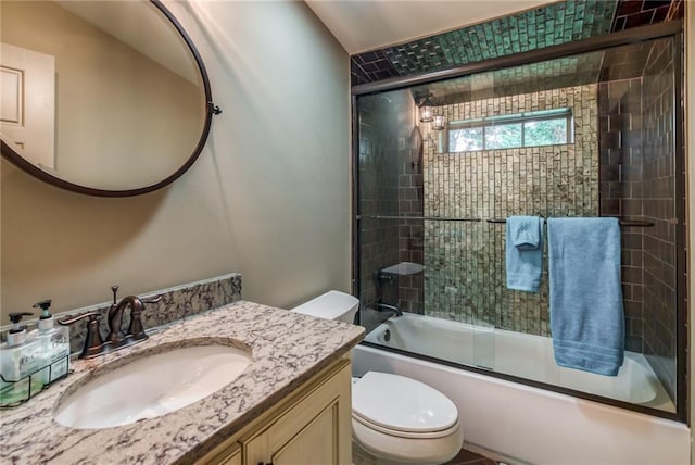 full bathroom with vanity, bath / shower combo with glass door, and toilet