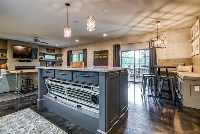 kitchen featuring a center island, hanging light fixtures, gray cabinetry, and ceiling fan with notable chandelier