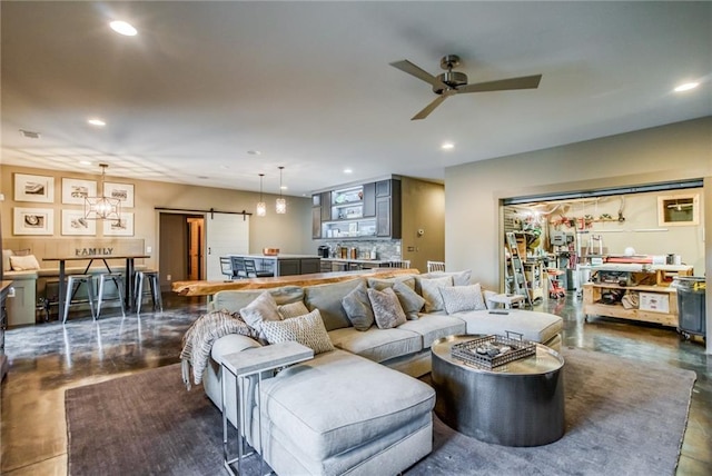 living room featuring a barn door and ceiling fan with notable chandelier