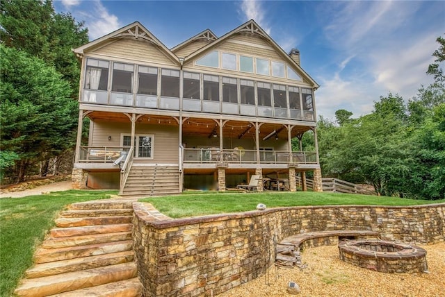 back of house with a lawn and a fire pit