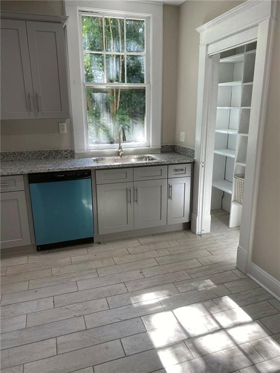 kitchen with sink, dishwasher, light wood-type flooring, and gray cabinets