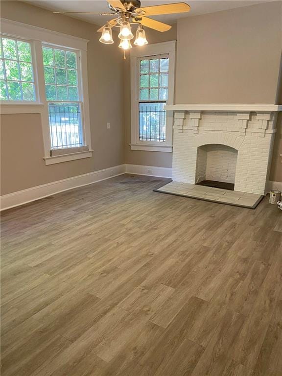 unfurnished living room with hardwood / wood-style floors, a fireplace, and ceiling fan