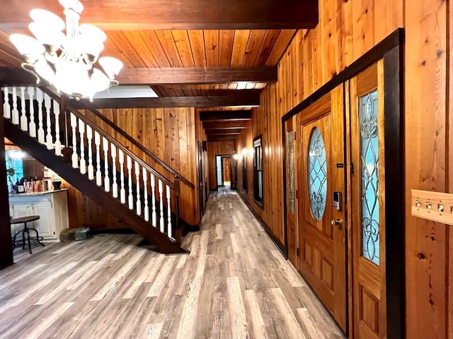 entryway featuring wooden walls, a notable chandelier, wood ceiling, and beam ceiling