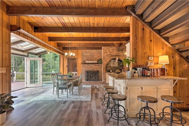 kitchen featuring wooden walls, white cabinetry, light stone counters, a kitchen breakfast bar, and light wood-type flooring