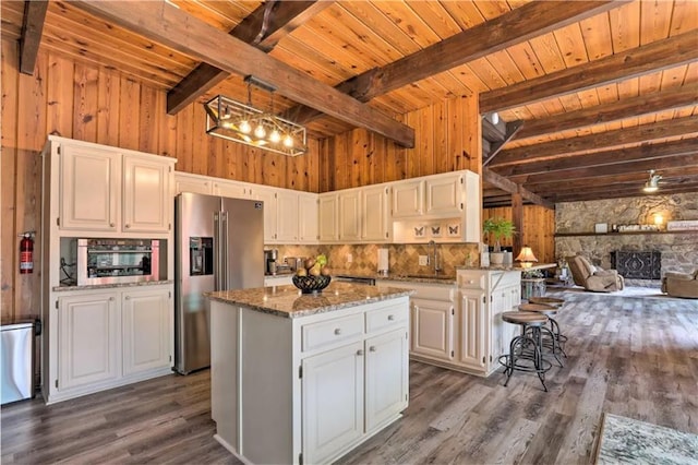 kitchen with a kitchen island, white cabinets, appliances with stainless steel finishes, and beamed ceiling