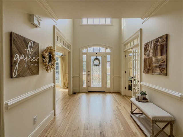 foyer entrance featuring baseboards, wood finished floors, and crown molding