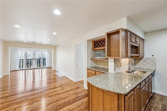 kitchen featuring light stone counters, sink, decorative backsplash, and light hardwood / wood-style flooring