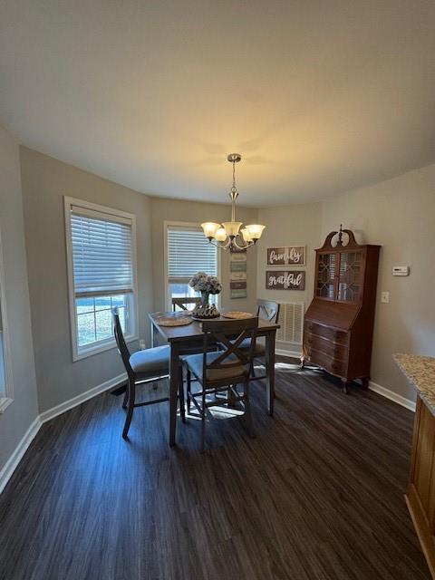 dining space with dark hardwood / wood-style floors and a notable chandelier