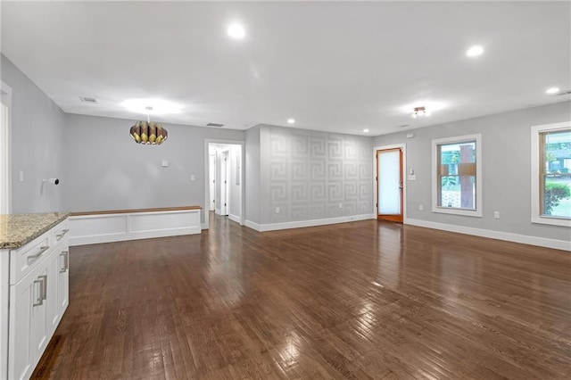 unfurnished living room featuring a notable chandelier and dark hardwood / wood-style flooring