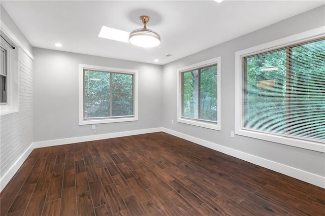 unfurnished room with hardwood / wood-style floors and a skylight