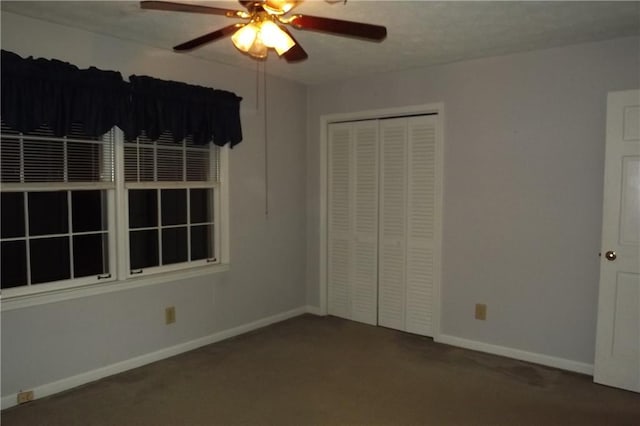 unfurnished bedroom featuring ceiling fan, dark carpet, and a closet