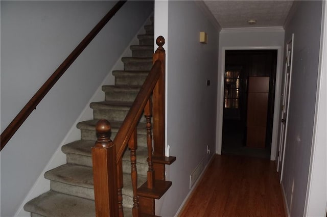 stairway with wood-type flooring and crown molding