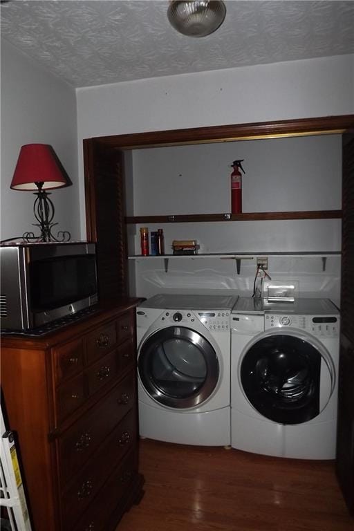 laundry room featuring a textured ceiling, dark wood-type flooring, and washing machine and clothes dryer