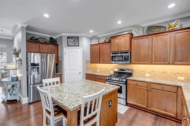 kitchen featuring a center island, light stone countertops, a kitchen breakfast bar, and appliances with stainless steel finishes