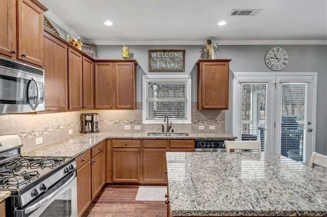 kitchen featuring sink, crown molding, appliances with stainless steel finishes, light stone countertops, and dark hardwood / wood-style flooring