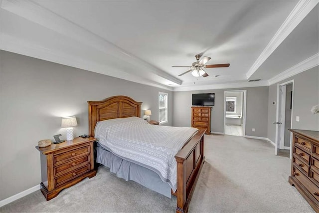 bedroom featuring ceiling fan, ensuite bathroom, ornamental molding, light colored carpet, and a raised ceiling