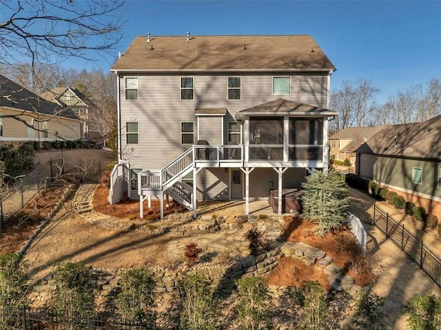 rear view of property with a wooden deck, a jacuzzi, and a sunroom