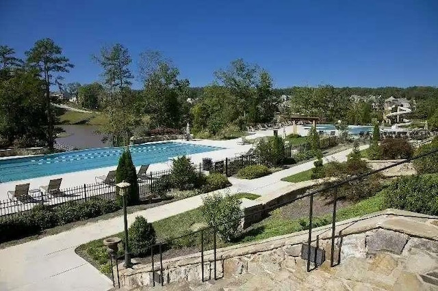 surrounding community with a water view and a pool