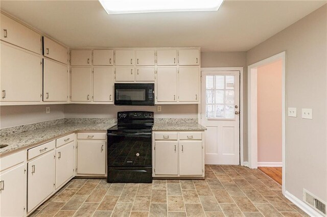 kitchen with light stone counters, white cabinets, and black appliances