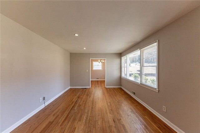 empty room with light hardwood / wood-style flooring and an inviting chandelier