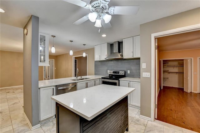 kitchen with wall chimney range hood, sink, ceiling fan, kitchen peninsula, and stainless steel appliances