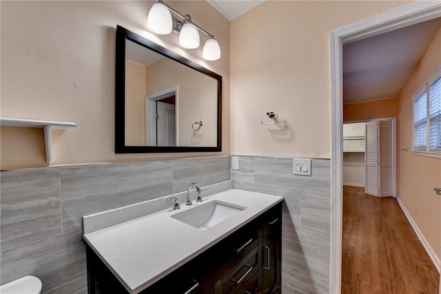 bathroom featuring wood-type flooring, vanity, and tile walls