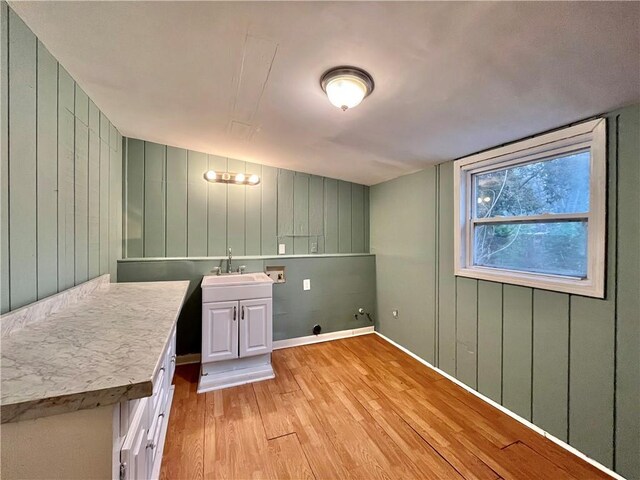 washroom featuring sink, washer hookup, cabinets, wooden walls, and light wood-type flooring