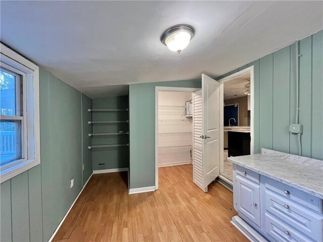 unfurnished bedroom featuring a spacious closet, sink, vaulted ceiling, and light wood-type flooring