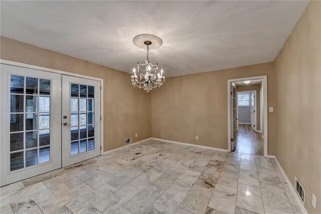 unfurnished dining area featuring french doors and an inviting chandelier