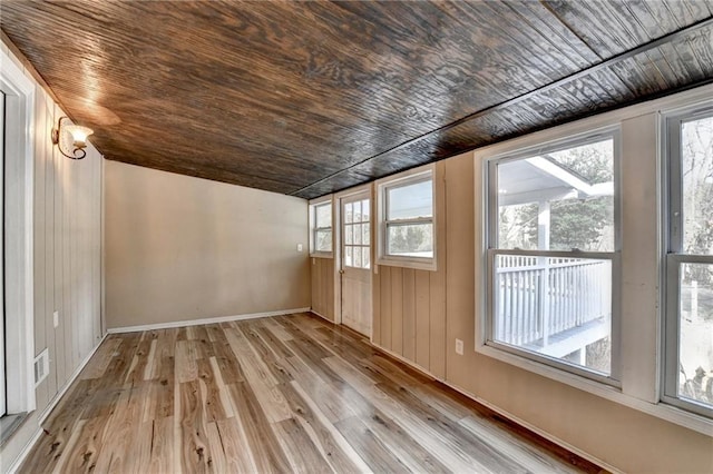 additional living space with wood walls, light hardwood / wood-style floors, wooden ceiling, and vaulted ceiling