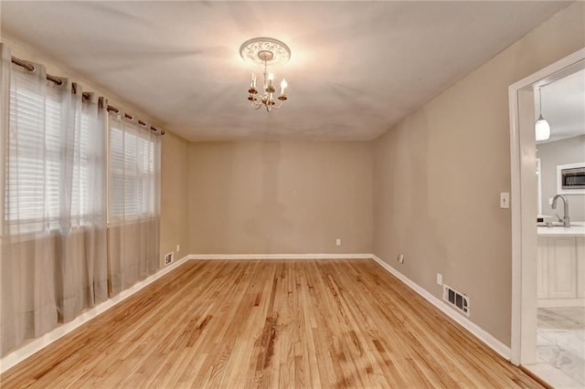 unfurnished room featuring wood-type flooring, sink, and a chandelier