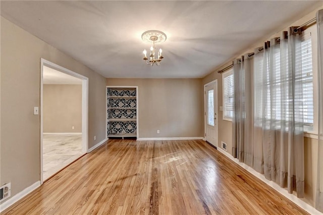 unfurnished room with hardwood / wood-style floors and a notable chandelier