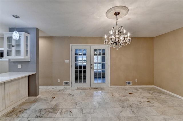 unfurnished dining area with an inviting chandelier and french doors