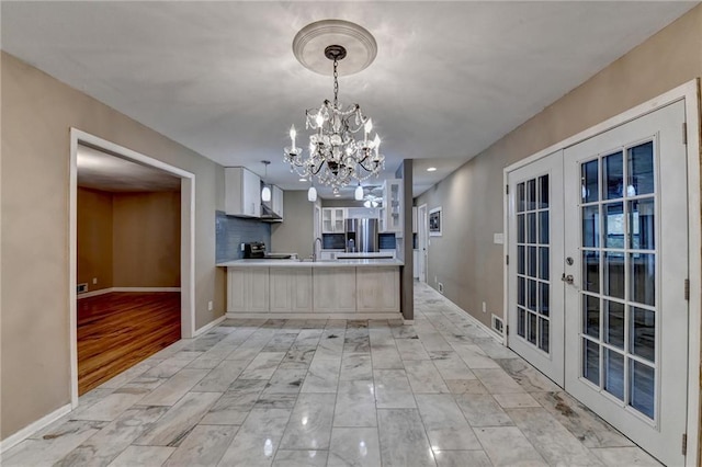 kitchen with french doors, sink, stainless steel fridge, light wood-type flooring, and a chandelier