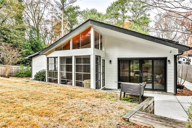 rear view of house featuring a patio, a sunroom, and a lawn