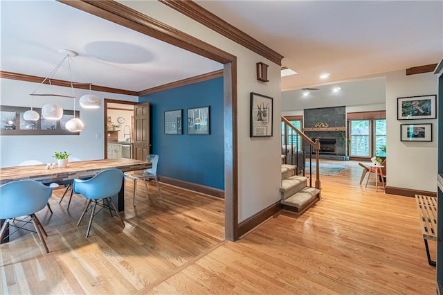 dining room featuring stairway, baseboards, crown molding, and light wood-style floors