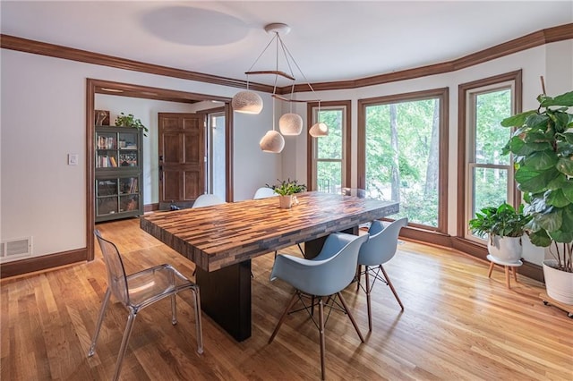 dining area with crown molding, baseboards, visible vents, and light wood finished floors