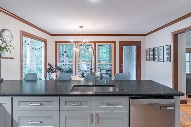 kitchen with stainless steel dishwasher, dark stone counters, a sink, a notable chandelier, and decorative light fixtures