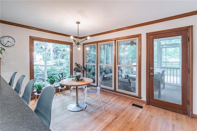 dining room with visible vents, ornamental molding, light wood finished floors, and a notable chandelier